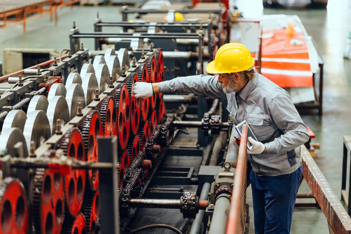 Senior engineer inspecting machinery in a metal plant